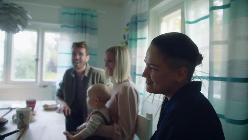 People sitting on chairs at a table in a room with windows in the background