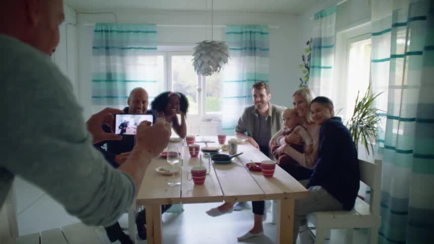 A group of people gather around a home dinning table posing for a photo