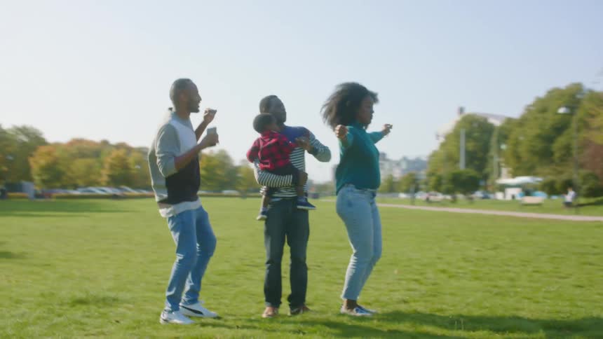 A man and his children dance together in a large open park