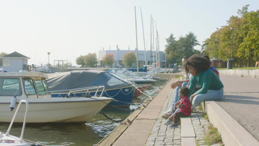 Family sits on step near docked boats