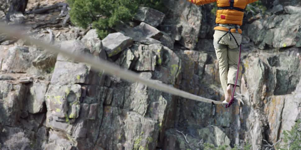 A man walks a tightrope over a ravine