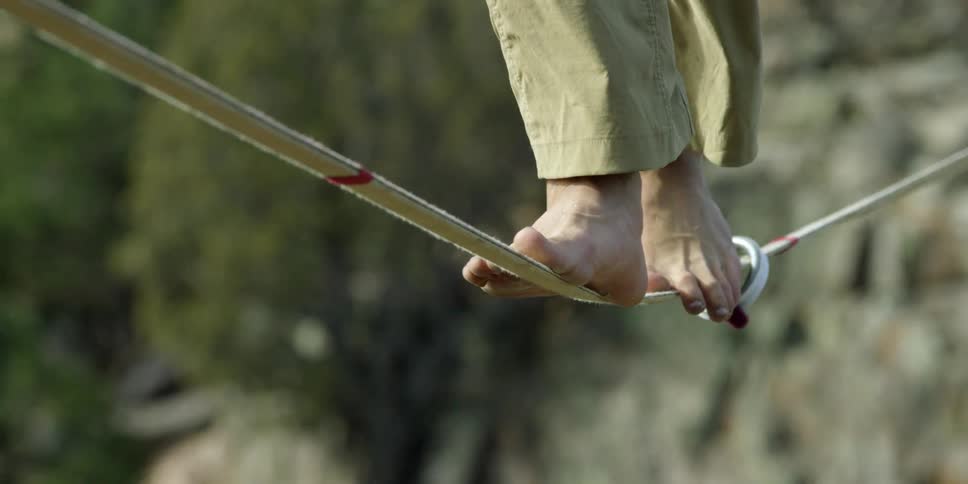 Close up of two feet walking over a tightrope