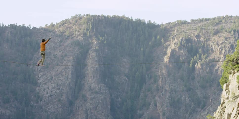 Person walking a high wire suspended over a deep canyon