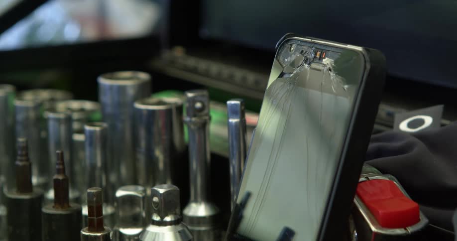 A close up of a tool box and a broken screen on a cell phone