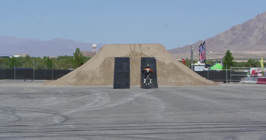 A person at a track goes over a jump on a motocross bike