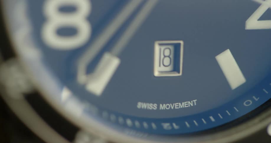 A close up of a blue face of a wrist watch with numbers text and hands visible