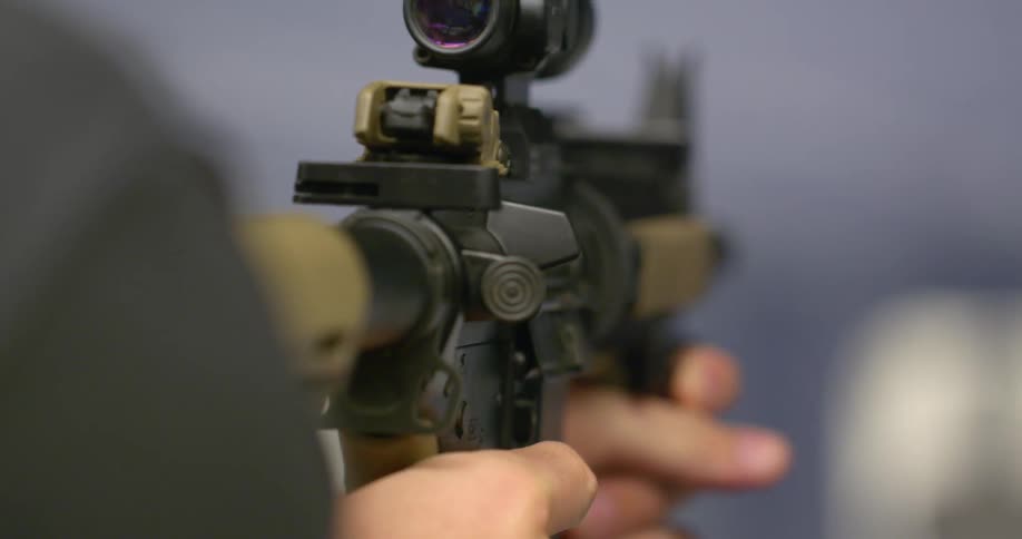 A soldier holds and aims a gun