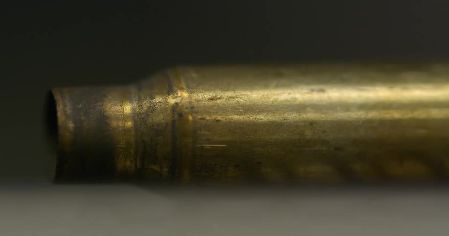 A single brass bullet sits on a gray surface