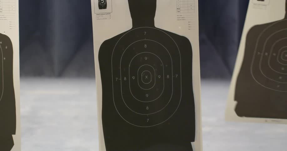 Paper shooting targets sway as they hang in the air in an indoor shooting range
