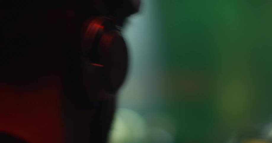 A man with headphones on in front of bright flashing lights