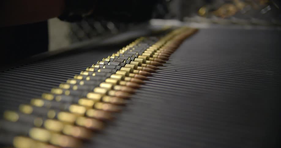 A man inserts bullets into a feeder for a machine gun