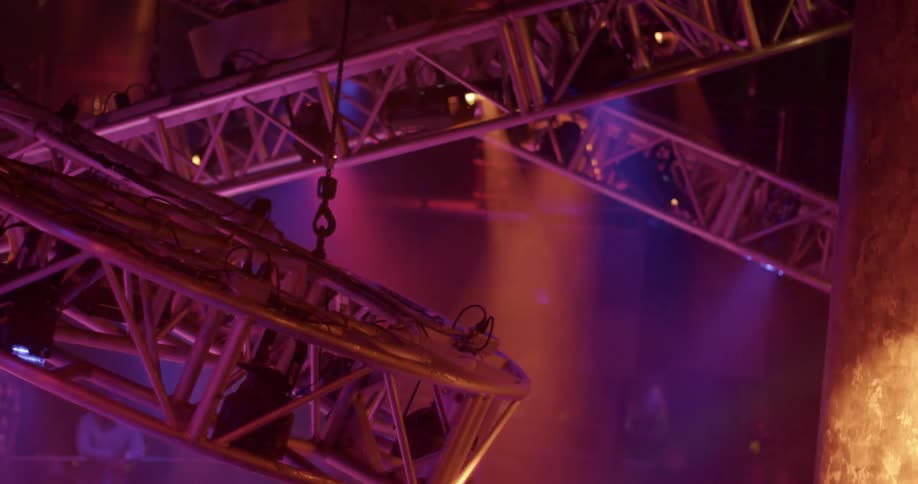 Moving rig holding colorful stage lights on the ceiling of a venue