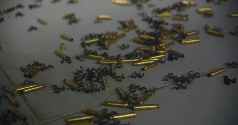 Close up of bullets and shell casings scattered on the tiled ground