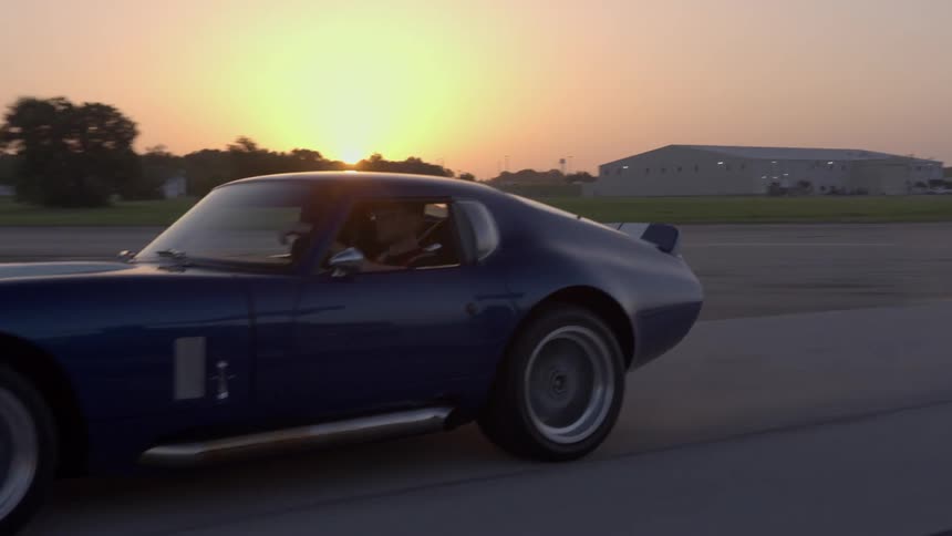 A man is driving his car in a rural area at dusk