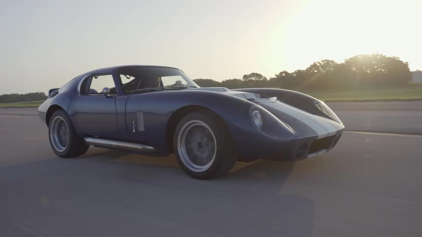 A blue sports car drives down a highway during the day
