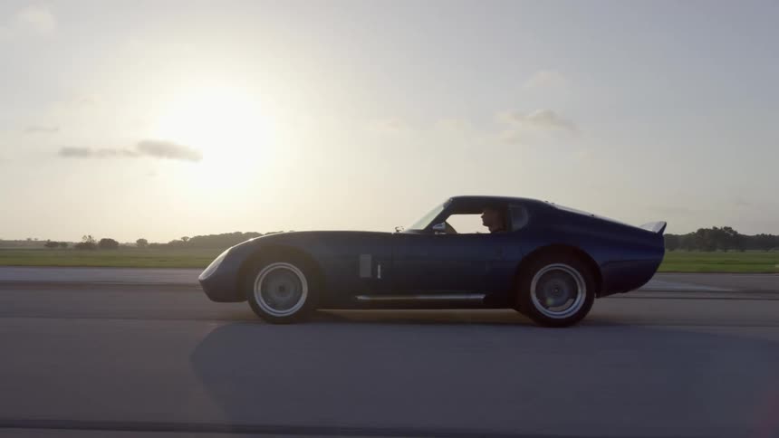 A person is driving a car on a road at dusk