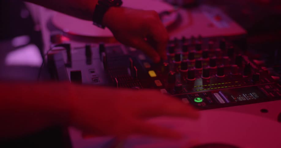 A disk jockey mixing music under the colorful strobing lights