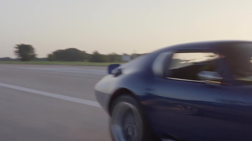 A car is driving on a road at dusk