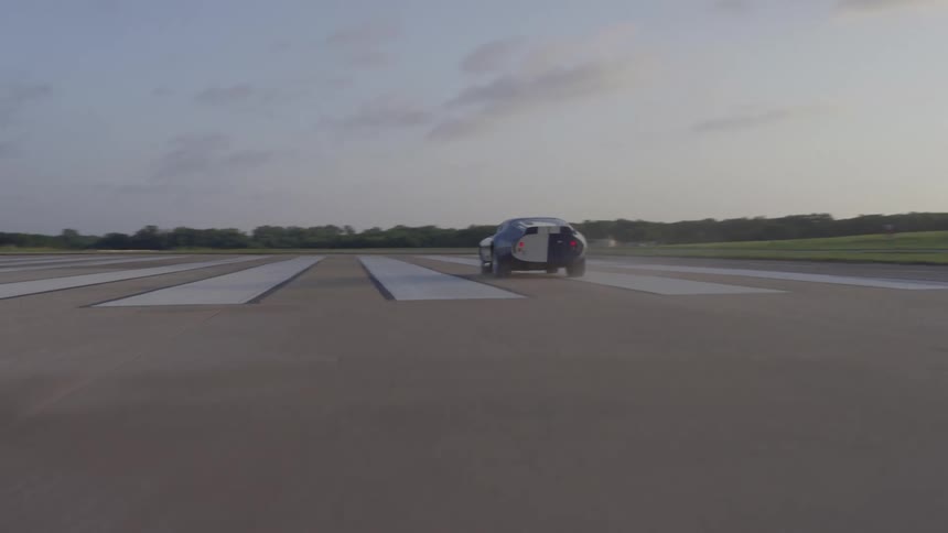 A blue sports car drives on white painted asphalt during the daytime