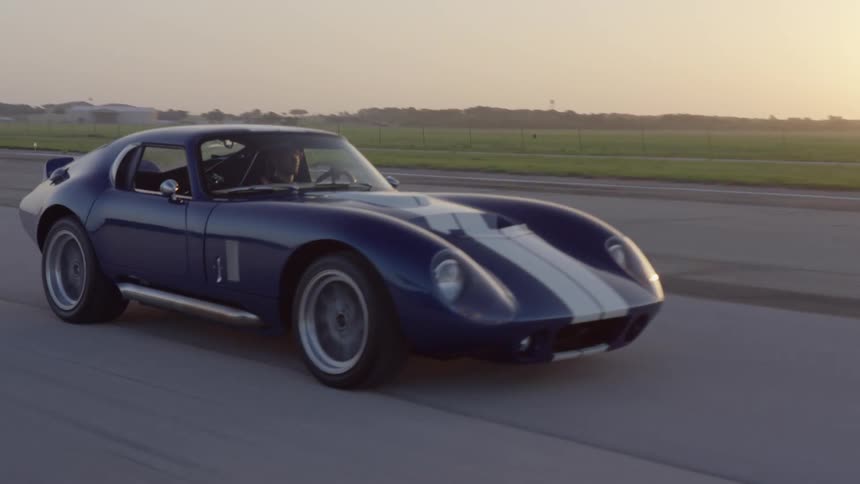 A roadster driving along the countryside at sunset