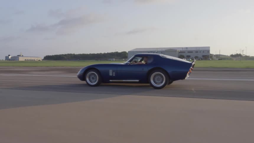 A sports car speeds down a race track roadway