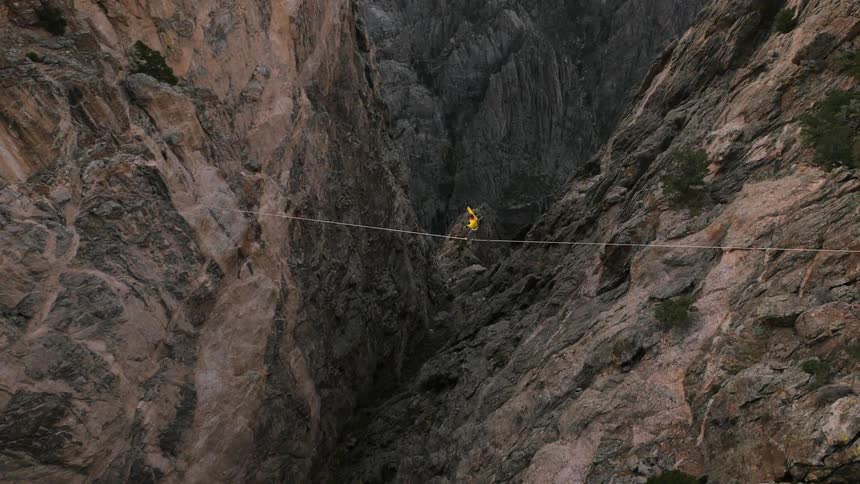 Aerial view of a person walking a tightrope over a mountain range
