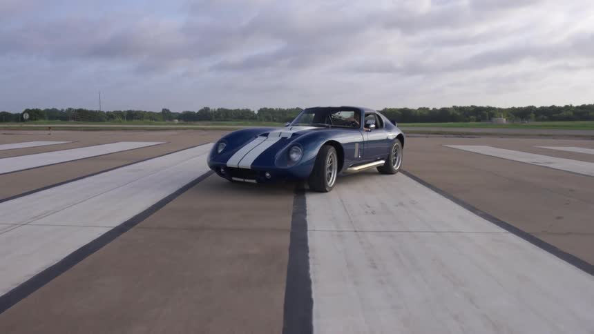 Blue shelby daytona coupe with white racing stripes on the runway