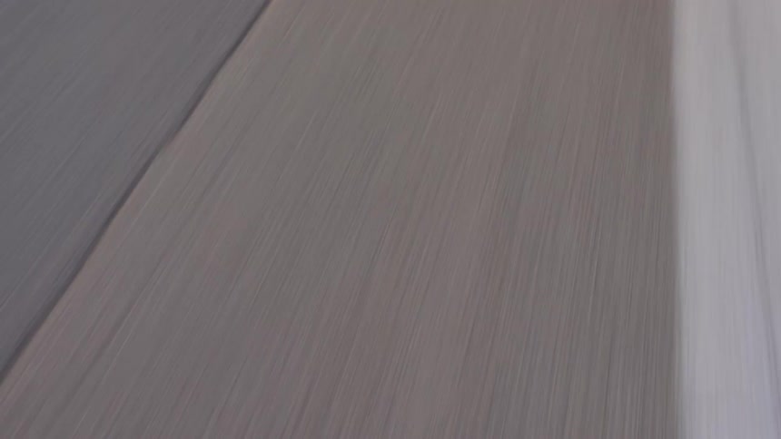 Blue race car with white stripes running down a runway at full speed