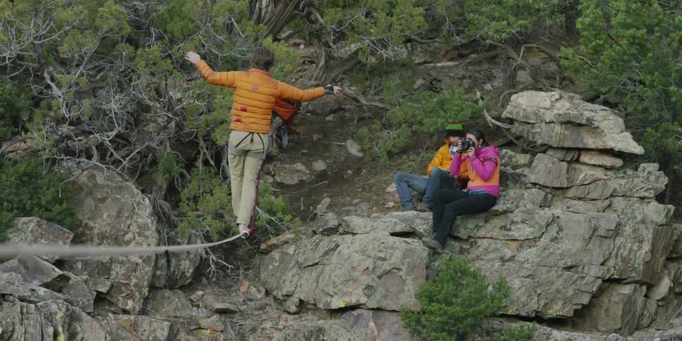 A man balances on a tightrope over a canyon