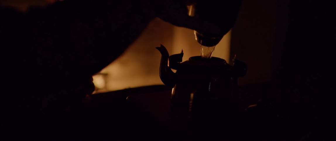 Person pouring water into the teapot is silhouetted against the fireplace in the room