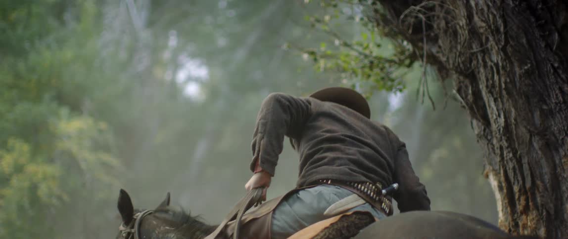 A man is sitting on a horse next to a tree