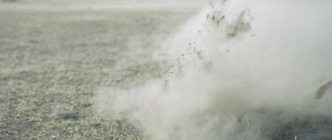 Close up of horse legs galloping over dirt kicking dust clouds