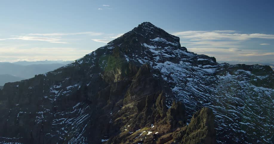 Aerial view of a snow covered peak in a mountain range in the morning