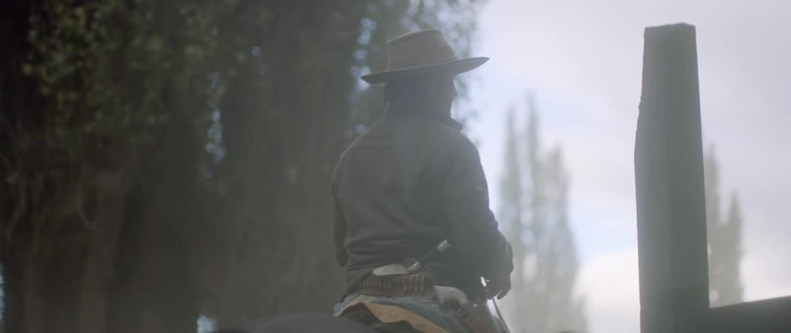 A rancher steers his horse through a wooden gate