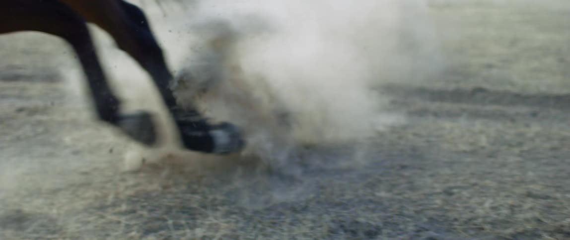 Black horse turns while galloping kicking up dust from the dirt