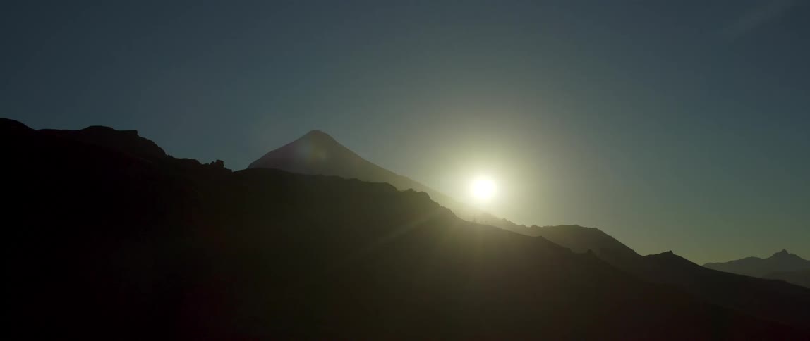 Landscape of mountains and hills with the sun low in the sky