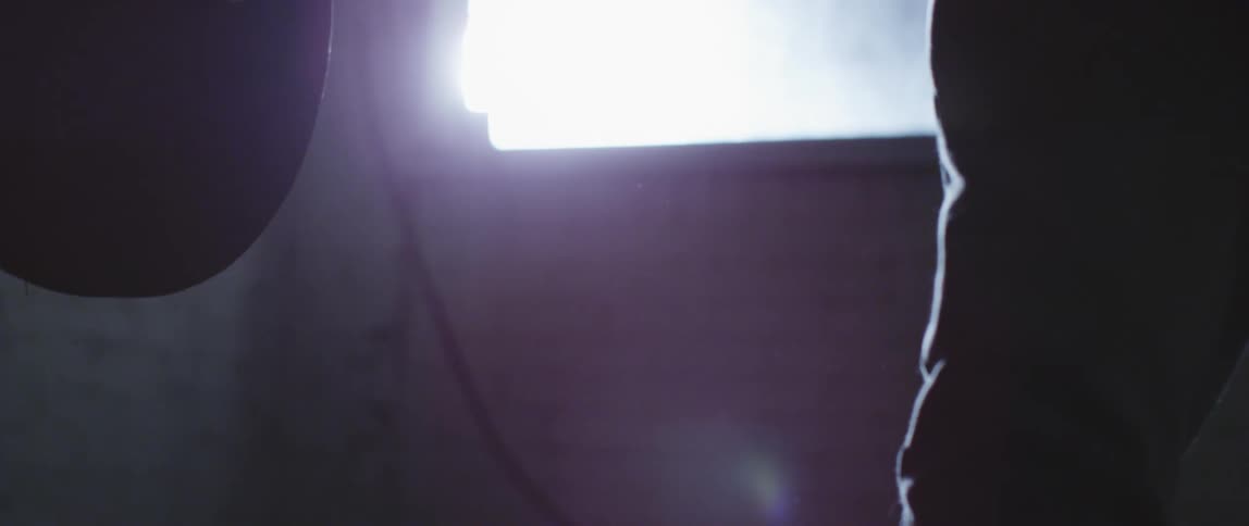 Close up of the silhouette of the hands of a person lifting weights in a dimly lit room