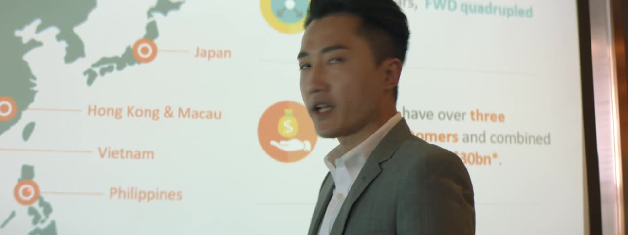 A professor stands in front of a white board that shows a map of asian countries