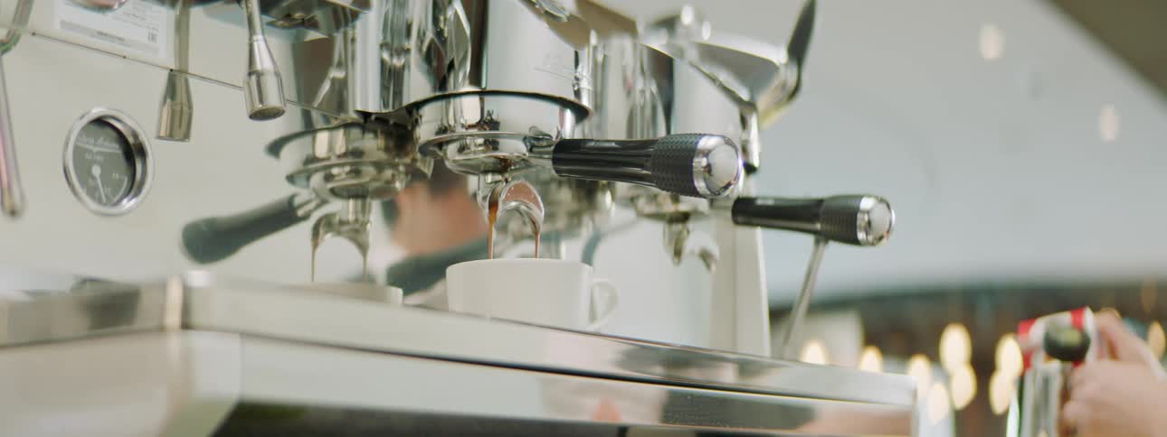 Espresso machine pouring hot coffee into a cup in a coffee shop