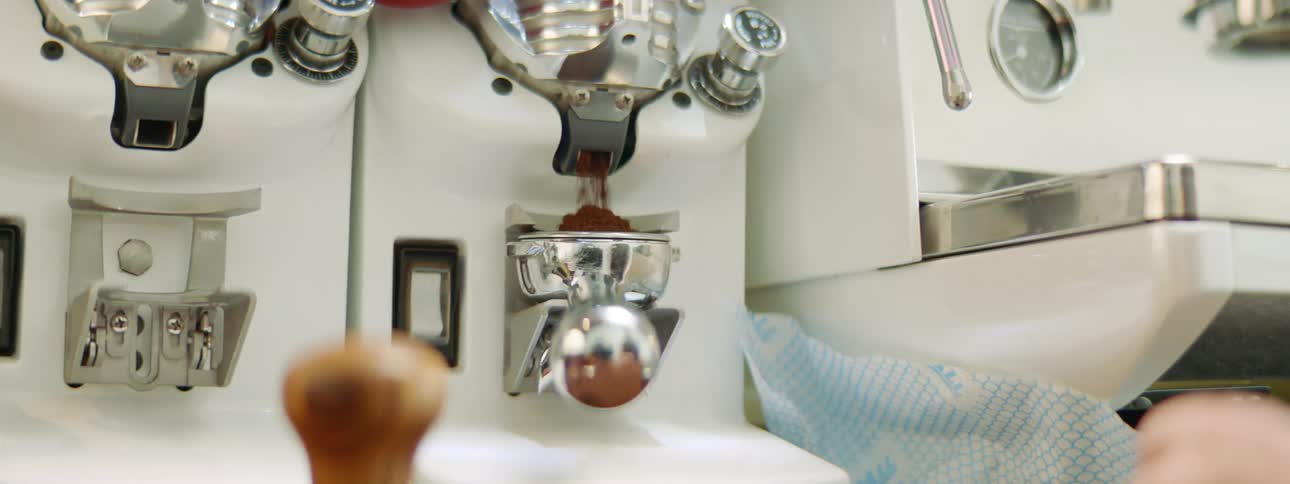 Woman serving ground coffee on a espresso filter on a shop