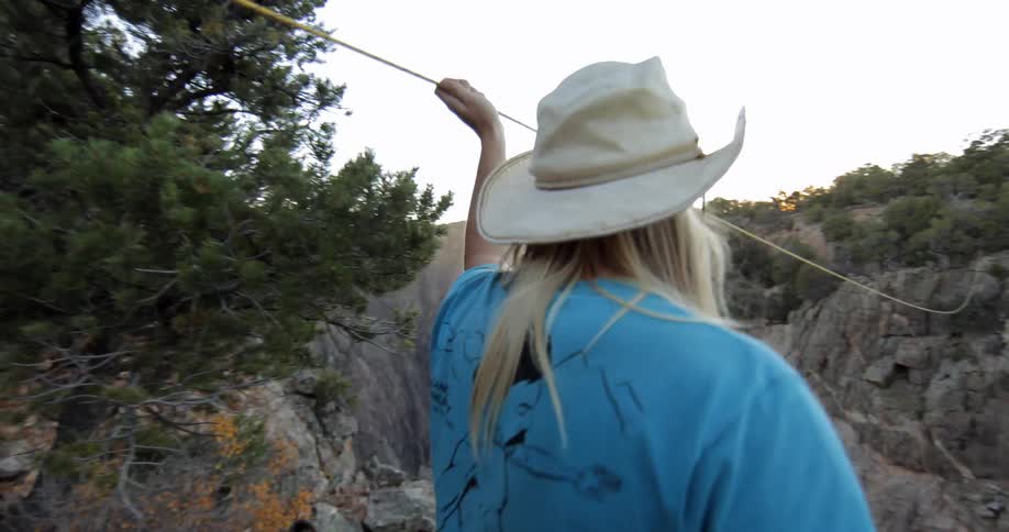 Man runs his hand against a tight rope suspended over a canyon