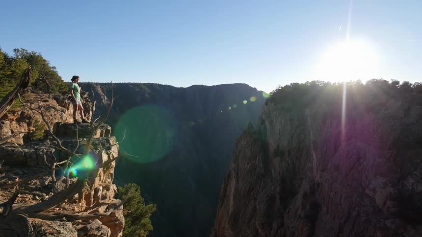 A woman stands on a rocky ledge