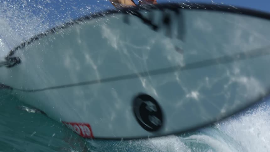 A male surfer rides along a wave and quickly cuts back to change direction