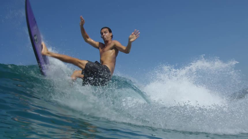 A surfer riding a wave on his surfboard attempts to make a sharp turn but fails and falls underwater