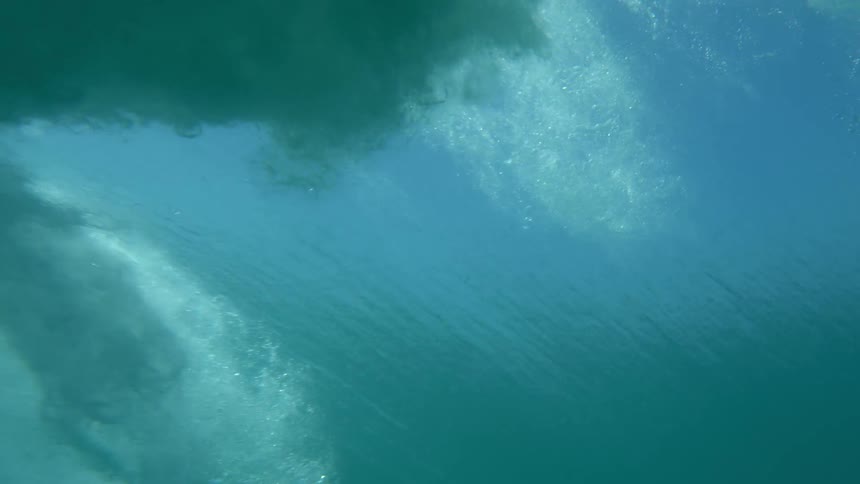 Underwater footage of sea waves passing over the camera on the green ocean waters