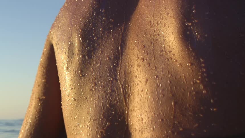 Water beads off the back of a man swimming in the ocean