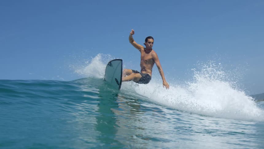 Young fit man surfing over an ocean wave near the coast at day