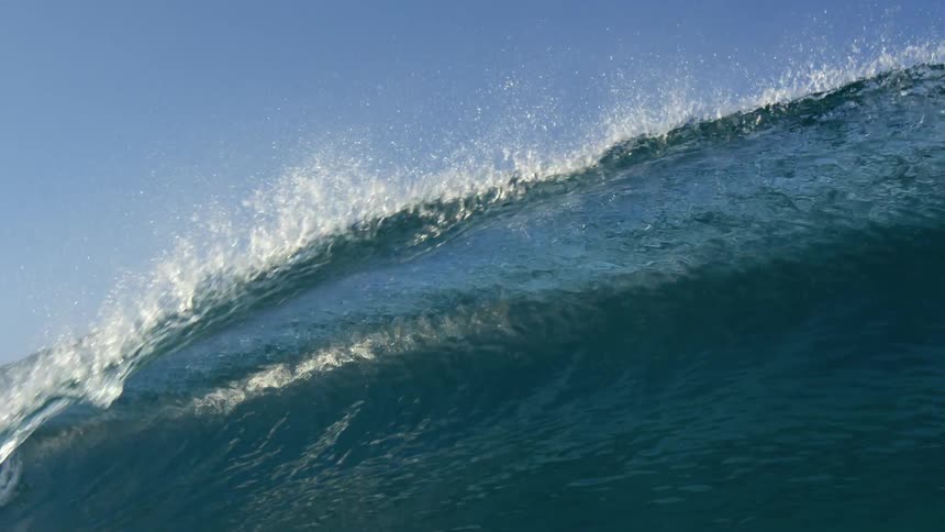 Wave crests and collapse forming a translucent sheet showing the blue of the sky instead the blue green of the ocean