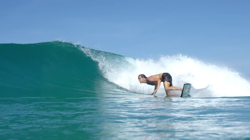 A young male surfer rides a large wave on which he quickly turns his board around
