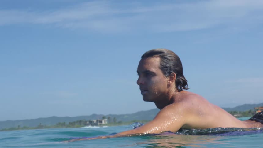 A man paddling his surfboard out in to the ocean